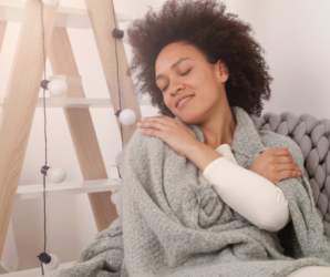 adult woman cozy in a blanket on a couch wearing a sweater